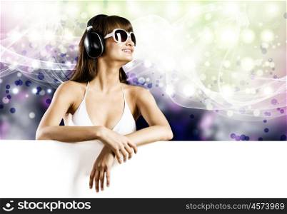 Girl with blank banner. Young woman in white bikini wearing headphones. Place for text