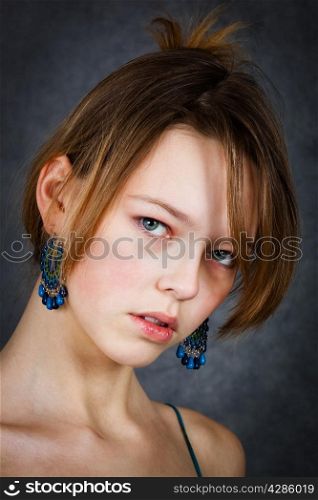 girl with blue earrings on a gray background