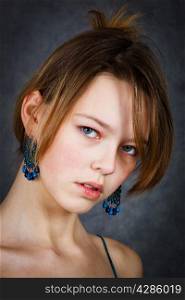 girl with blue earrings on a gray background