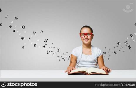 Girl with book. Cute girl of school age in glasses reading book