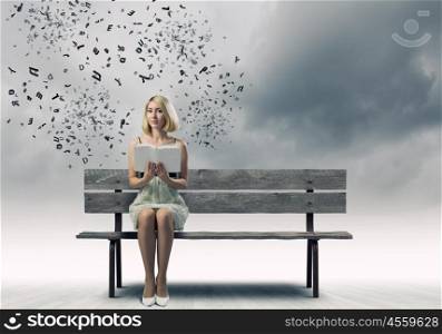 Girl with book. Young pretty woman sitting on bench and reading book