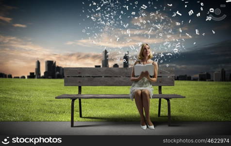 Girl with book. Young pretty woman sitting on bench and reading book