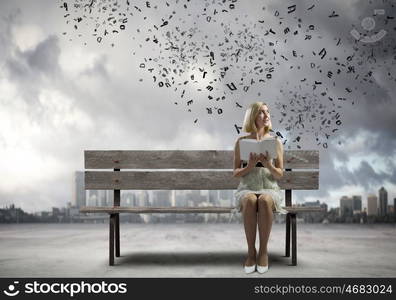 Girl with book. Young pretty woman sitting on bench and reading book