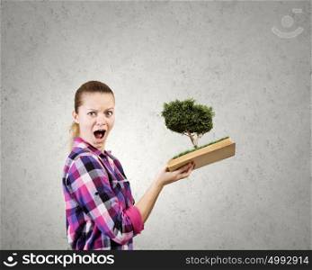 Girl with book. Young woman in casual holding opened book with green tree