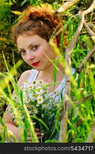 Girl with camomile bunch stand neat the wooden fence. Rural portrait.