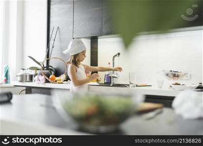 girl with chef hat washing her hand faucet home