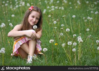 girl with dandelion and green meadow in the background