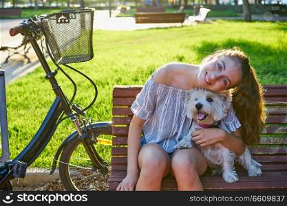 Girl with dog sitting in a park bench with turf grass background outdoor