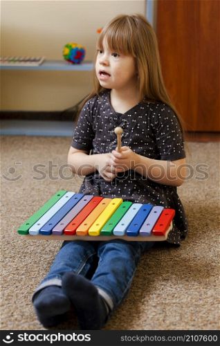 girl with down syndrome playing with colorful xylophone