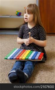 girl with down syndrome playing with colorful xylophone