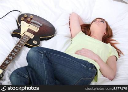 Girl with electric guitar in bedroom