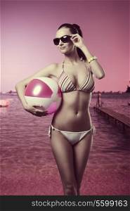 girl with fashion summer style, sexy bikini, sunglasses and wrist watch posing with beach ball under the arm