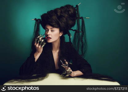 girl with fluffy hair sitting at the table and paints lips