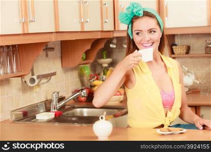 Girl with gingerbread cookies drinking tea coffee.. Pretty pin up girl with heart shape gingerbread cookies drinking tea or coffee at home. Gorgeous young retro woman with hot beverage relaxing in kitchen.