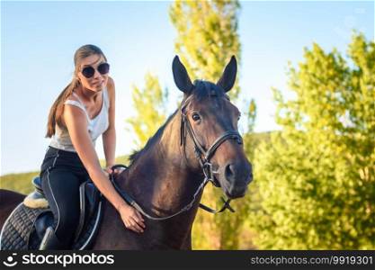Girl with glasses strokes a horse on a horse ride