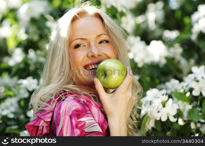 girl with green apple on a background of white flowers