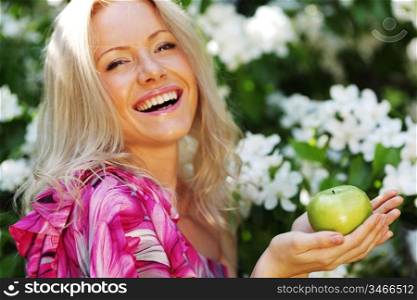 girl with green apple on a background of white flowers