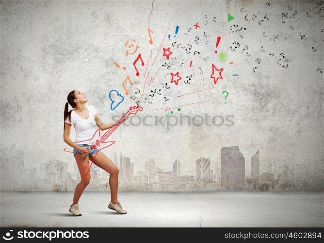 Girl with guitar. Young girl in shorts playing on imaginary guitar