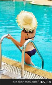 Girl with hat in tropical swimming pool