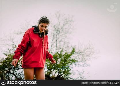 Girl with headphones and raincoat washing her waterproof boots