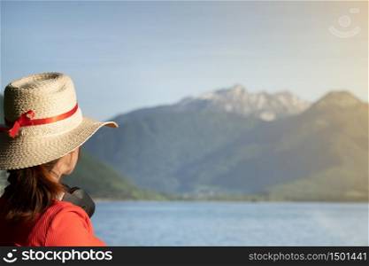 Girl with headphones and stalk hat and red dress on looking a the mountains by a lake. Lifestyle concept