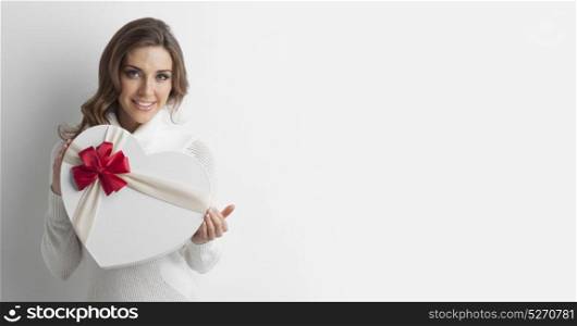 Girl with heart-shaped box. Young girl with heart-shaped gift box on white background