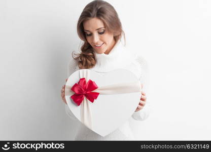 Girl with heart-shaped box. Young girl with heart-shaped gift box on white background