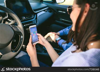Girl with her boyfriend using the cell phone in the car. Girl and boyfriend using mobile in the car
