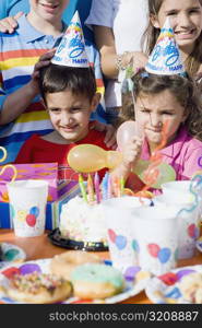 Girl with her friends standing in front of a birthday cake