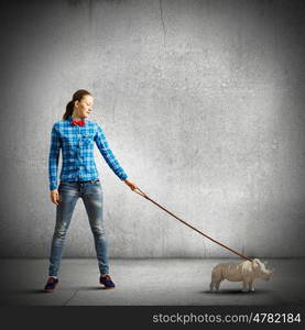 Girl with kangaroo. Young woman in casual holding rhino on lead