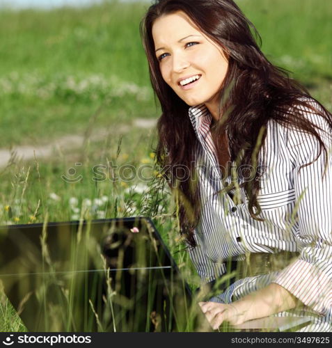 girl with laptop on green grass