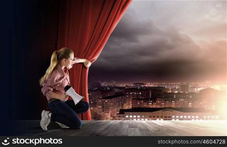 Girl with megaphone. Young girl on stage with megaphone opening red curtain