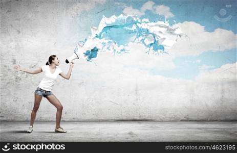 Girl with megaphone. Young teenager girl in shorts screaming in megaphone