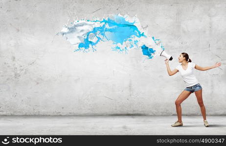 Girl with megaphone. Young teenager girl in shorts screaming in megaphone