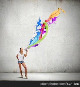 Girl with megaphone. Young woman in casual speaking in megaphone with colorful splashes flying out