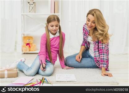 girl with mother drawing paper floor