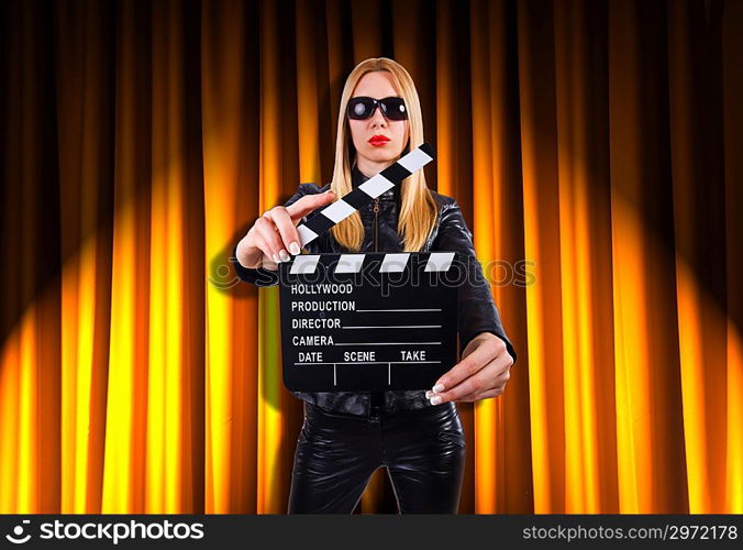 Girl with movie board against curtains