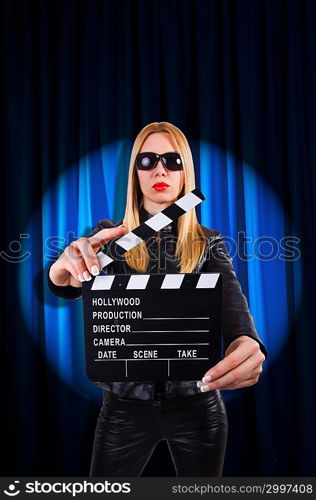 Girl with movie board against curtains