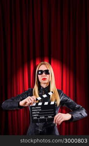 Girl with movie board against curtains