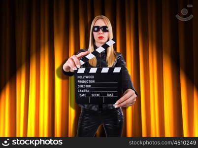 Girl with movie board against curtains