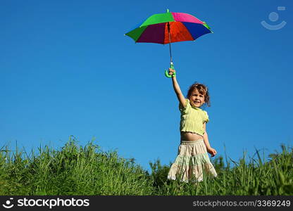 girl with multicoloured umbrella in lifted hand in grass