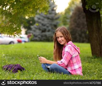 Girl with notebook sitting at the grass