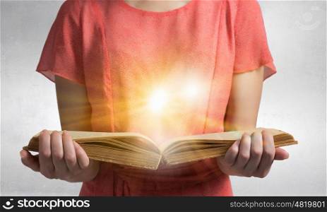 Girl with opened red book. Close view of woman holding opened book and light coming from pages