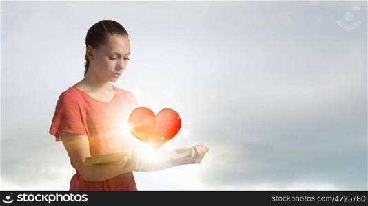 Girl with opened red book. Young woman holding opened book and red heart on pages