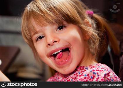 Girl with pink candy on tongue