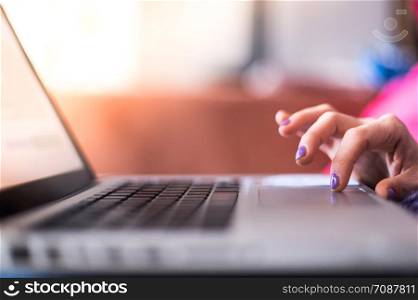 Girl with purple fingernails is using her laptop at home on the couch