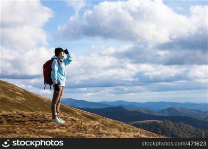 Girl with red backpack standing at the mountain top and watching mountain panorama. Carpathians Mountains, Ukraine.. Girl with red backpack standing at the mountain top and watching mountain panorama