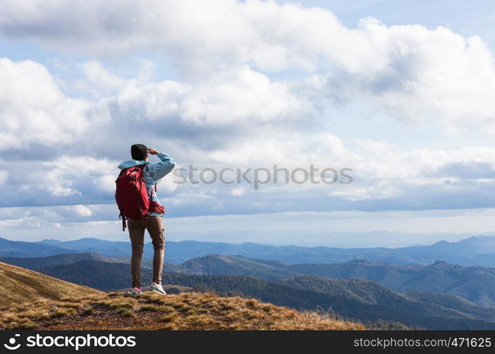 Girl with red backpack standing at the mountain top and watching mountain panorama. Carpathians Mountains, Ukraine.. Girl with red backpack standing at the mountain top and watching mountain panorama