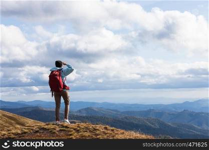 Girl with red backpack standing at the mountain top and watching mountain panorama. Carpathians Mountains, Ukraine.. Girl with red backpack standing at the mountain top and watching mountain panorama