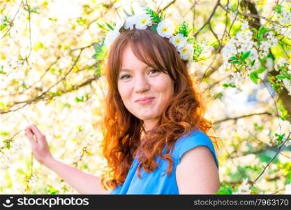 girl with red hair on the background of blossoming cherry in the park